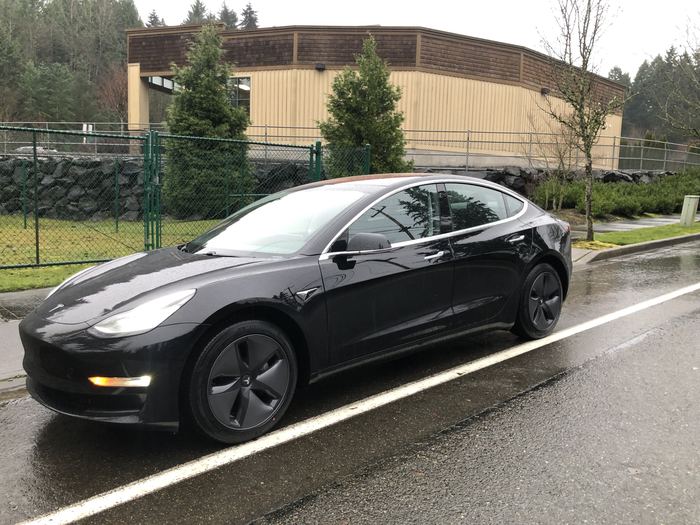 Zach's first Tesla, a black 2018 Model 3, parked on a residential street.